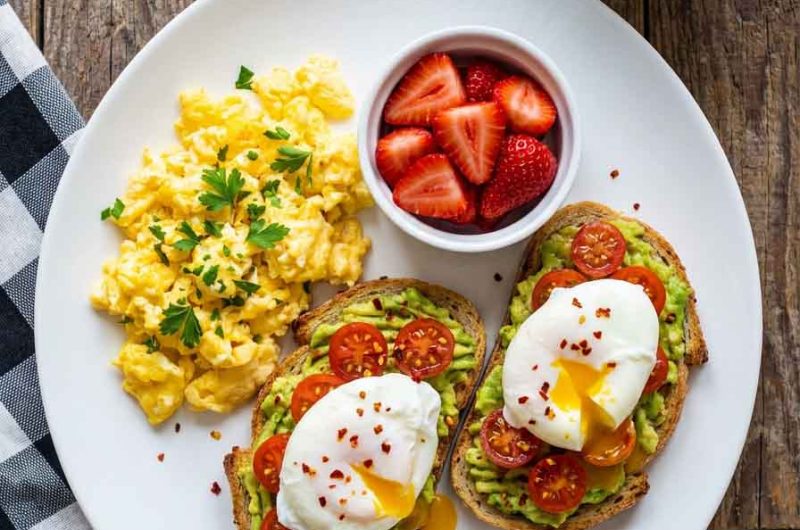 Healthy scrambled eggs with strawberries and avocado toast on a plate.Healthy Breakfast