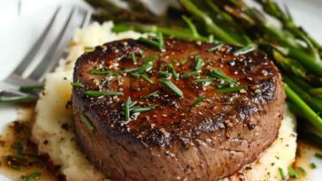 Pan-seared filet mignon with a golden crust, topped with garlic herb butter and served with roasted vegetables.