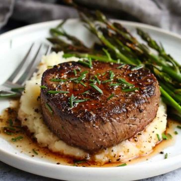 Pan-seared filet mignon with a golden crust, topped with garlic herb butter and served with roasted vegetables.