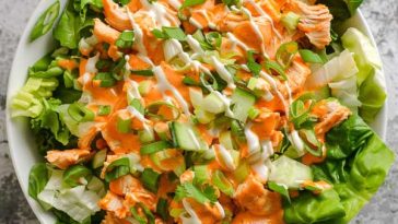 A bowl of buffalo chicken salad with spicy grilled chicken, crisp romaine, celery, cherry tomatoes, and a drizzle of ranch dressing.