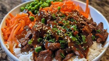 Easy Korean beef bowl with savory ground beef, steamed rice, sliced green onions, sesame seeds, and a drizzle of soy garlic sauce, served in a ceramic bowl.