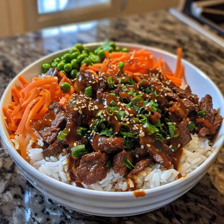 Easy Korean beef bowl with savory ground beef, steamed rice, sliced green onions, sesame seeds, and a drizzle of soy garlic sauce, served in a ceramic bowl.