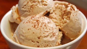 Creamy homemade cinnamon ice cream scooped into a bowl with a sprinkle of cinnamon.