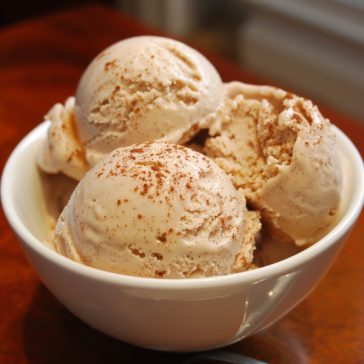 Creamy homemade cinnamon ice cream scooped into a bowl with a sprinkle of cinnamon.