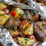 Juicy steak and tender potatoes cooked in foil packets with herbs and butter, ready to serve.