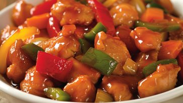 Crispy chicken pieces coated in glossy sweet and sour sauce with bell peppers and pineapple chunks, served over steamed rice.