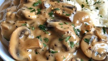 Homemade mushroom gravy in a saucepan with fresh herbs