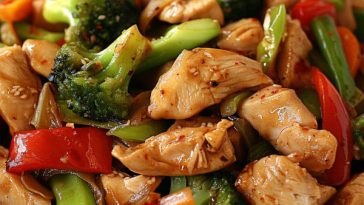 A colorful chicken stir-fry with tender chicken pieces, bell peppers, broccoli, carrots, and snap peas tossed in a savory Asian sauce, served over steamed rice.