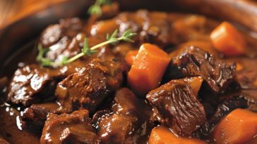 Hearty beef and Guinness stew with tender beef, carrots, and potatoes simmered in a rich dark gravy.
