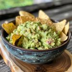 Fresh guacamole made with ripe avocados, lime, and herbs in a bowl.