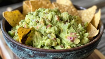 Fresh guacamole made with ripe avocados, lime, and herbs in a bowl.