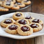 Buttery thumbprint cookies filled with jam centers and lightly dusted with powdered sugar.