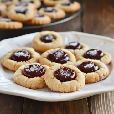 Buttery thumbprint cookies filled with jam centers and lightly dusted with powdered sugar.