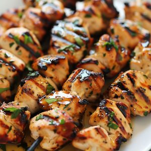 Grilled garlic chicken skewers with charred edges and herbs.