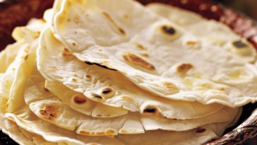 Stack of soft homemade flour tortillas, warm and flexible, lightly browned and ready to serve.