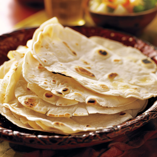 Stack of soft homemade flour tortillas, warm and flexible, lightly browned and ready to serve.