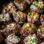 Juicy garlic butter steak bites seared to perfection in a skillet, coated in rich garlic butter and garnished with fresh herbs.