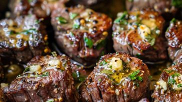Juicy garlic butter steak bites seared to perfection in a skillet, coated in rich garlic butter and garnished with fresh herbs.