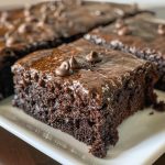 Moist chocolate zucchini cake with a rich crumb, topped with chocolate frosting and sliced to show texture.
