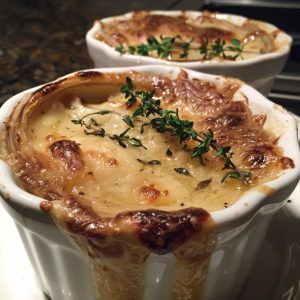 French onion soup gratinée with caramelized onions, rich broth, toasted bread, and melted cheese on top.