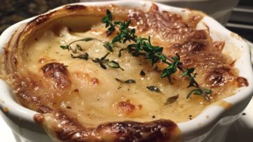 French onion soup gratinée with caramelized onions, rich broth, toasted bread, and melted cheese on top.