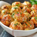 Cheesy chicken meatballs baked until golden, with melted cheese inside and herbs on top.