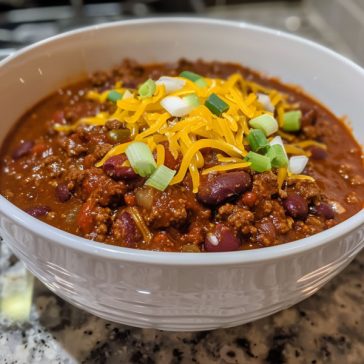 Hearty bowl of chili topped with cheese and fresh herbs.