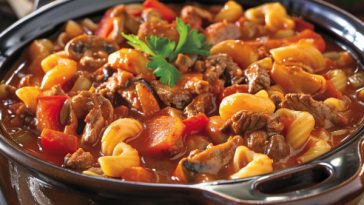 Classic goulash made with ground beef, pasta, tomato sauce, and herbs served warm in a bowl.