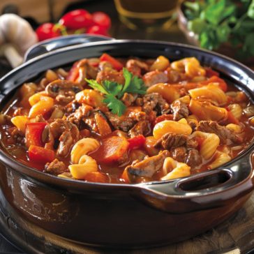 Classic goulash made with ground beef, pasta, tomato sauce, and herbs served warm in a bowl.