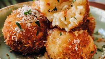 Golden crispy arancini rice balls filled with gooey cheese and rice, served with marinara sauce for dipping.