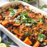 Smoky sweet potato and black bean casserole baked with spices, topped with herbs, and served warm in a dish.