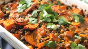 Smoky sweet potato and black bean casserole baked with spices, topped with herbs, and served warm in a dish.