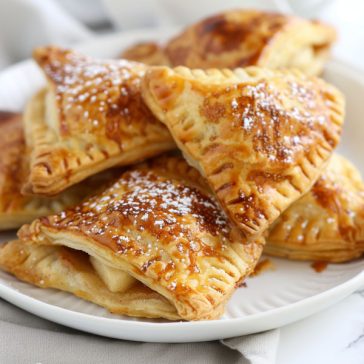 Golden apple turnovers filled with cinnamon apples and flaky pastry, lightly glazed on top.