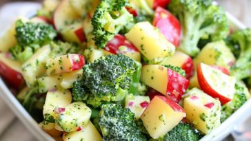 A colorful bowl of broccoli apple salad with fresh broccoli florets, crisp apple slices, dried cranberries, sunflower seeds, and a creamy dressing.