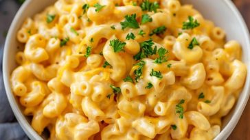 A creamy pot of homemade mac and cheese with elbow pasta coated in rich cheese sauce, served hot in a rustic pot and topped with extra melted cheese.