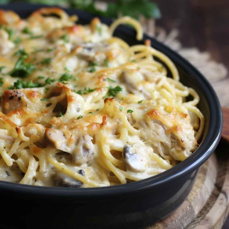 Creamy turkey tetrazzini baked in a casserole dish with golden cheese topping, spaghetti noodles, and fresh parsley garnish.