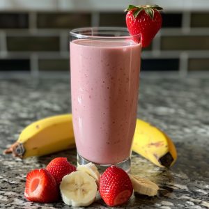 Creamy strawberry banana smoothie blended with fresh strawberries, ripe banana, and milk in a glass.