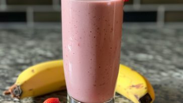 Creamy strawberry banana smoothie blended with fresh strawberries, ripe banana, and milk in a glass.