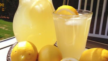 Fresh homemade lemonade served over ice with lemon slices in a glass.