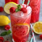Refreshing raspberry lemonade with fresh raspberries, lemon slices, and ice in a glass.