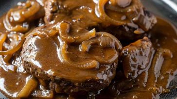 A juicy hamburger steak smothered in rich brown gravy with caramelized onions, served alongside mashed potatoes and green beans.