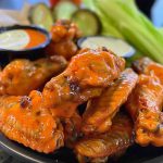 Crispy buffalo chicken wings coated in spicy sauce, served with celery sticks and a side of creamy ranch dressing.