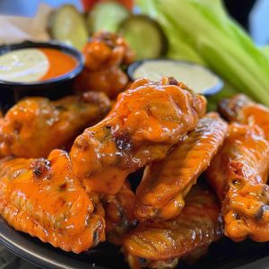 Crispy buffalo chicken wings coated in spicy sauce, served with celery sticks and a side of creamy ranch dressing.