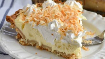 A slice of easy coconut cream pie with a golden crust, fluffy whipped topping, and toasted coconut flakes, served on a white dessert plate.