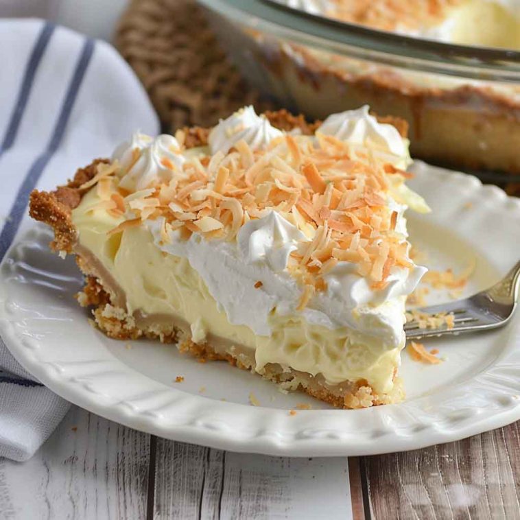 A slice of easy coconut cream pie with a golden crust, fluffy whipped topping, and toasted coconut flakes, served on a white dessert plate.