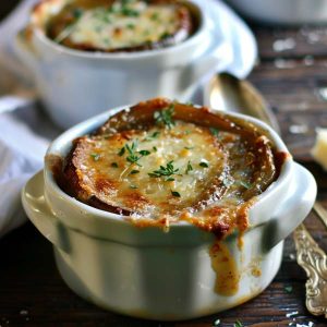 A bowl of French onion soup topped with golden, melted Gruyère cheese and toasted baguette slices, served hot and bubbling.