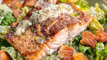 Salmon Caesar Salad with grilled salmon fillet, crisp romaine lettuce, parmesan cheese, crunchy croutons, and creamy Caesar dressing, served in a rustic bowl.