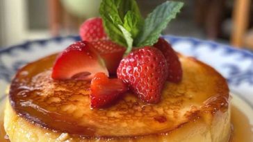 A smooth, golden Spanish flan topped with glossy caramel sauce, served on a white dessert plate.