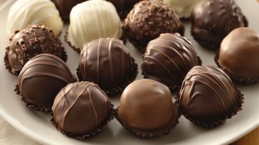 Homemade chocolate truffles rolled in cocoa powder and sprinkles, displayed elegantly on a dessert platter.
