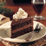 Rich frosted fudge cake with layers of moist chocolate sponge, creamy fudge frosting, and a glossy finish.